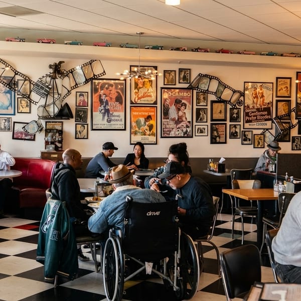Diners seated at tables and booths in a retro-themed restaurant with movie posters and film strips on the walls.