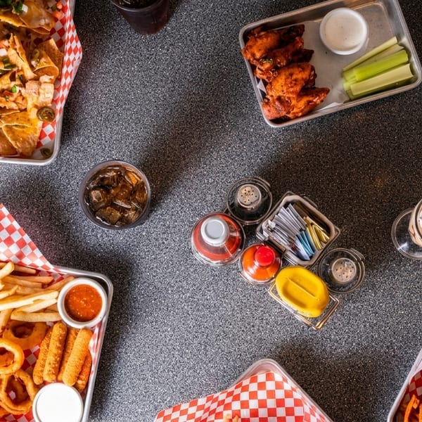 Overhead view of various diner foods: nachos, wings, fries, onion rings, burger, and sweet potato fries.
